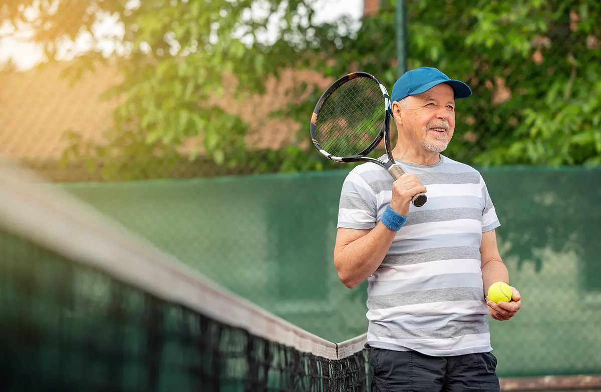 Happy man playing tennis after having successful testosterone therapy