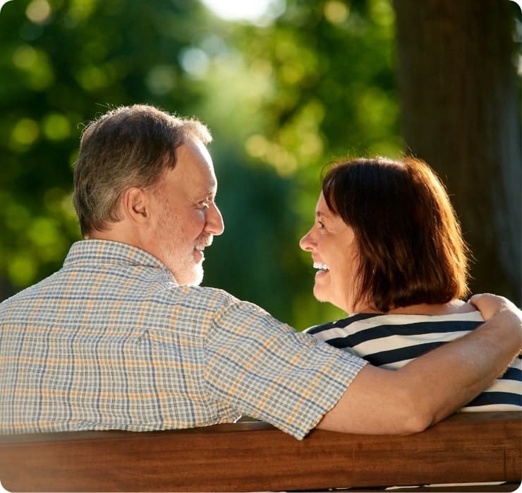 Elderly couple smiling on a park bench after participating in a clinical trial